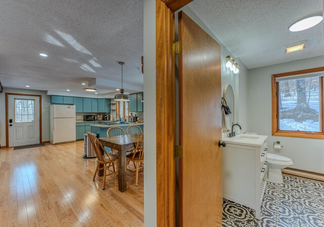 bathroom with baseboards, wood-type flooring, a textured ceiling, and vanity