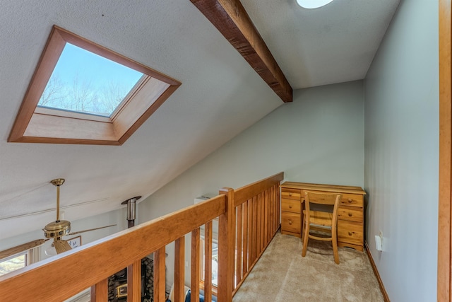 hallway with vaulted ceiling with skylight, baseboards, and carpet floors