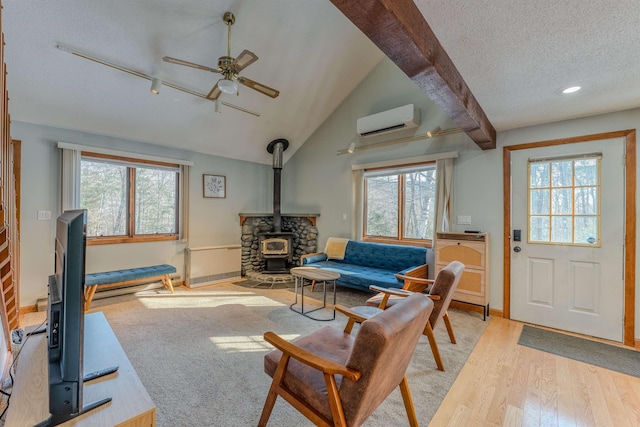 living room featuring a wall mounted air conditioner, a textured ceiling, light wood finished floors, lofted ceiling, and a wood stove