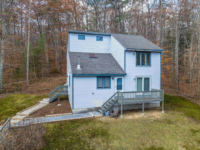 back of property featuring a deck, stairs, a lawn, and roof with shingles