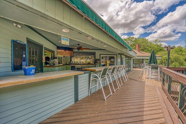 wooden terrace with a ceiling fan and outdoor dry bar