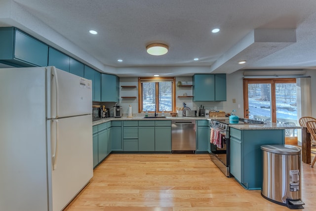 kitchen with open shelves, light wood-type flooring, a peninsula, stainless steel appliances, and a sink