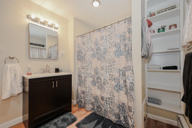 full bath featuring a baseboard heating unit, baseboards, wood finished floors, and vanity