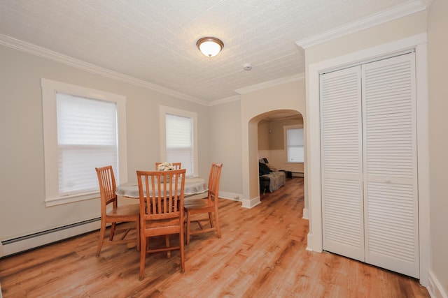 dining space featuring arched walkways, a healthy amount of sunlight, and a baseboard radiator