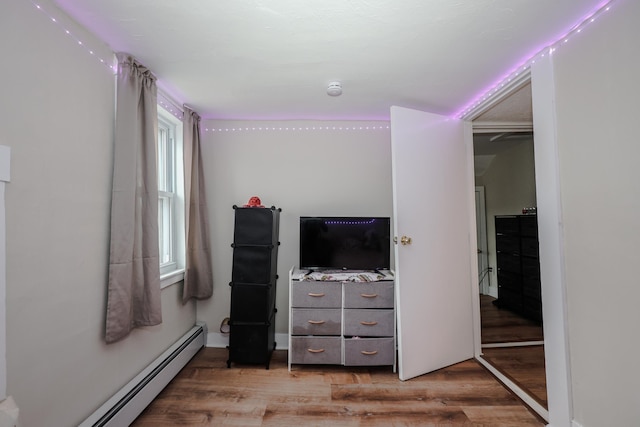 bedroom with light wood-type flooring and baseboard heating