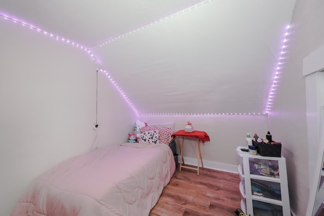 bedroom featuring lofted ceiling, wood finished floors, and baseboards