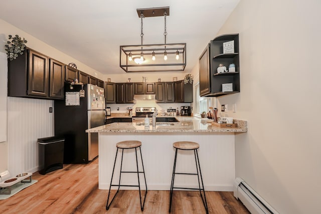 kitchen featuring light wood finished floors, under cabinet range hood, baseboard heating, a peninsula, and stainless steel appliances