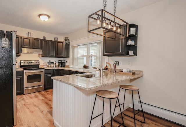 kitchen with a baseboard heating unit, under cabinet range hood, appliances with stainless steel finishes, a peninsula, and a sink