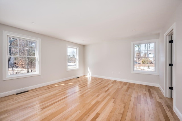 spare room featuring visible vents, light wood-type flooring, and baseboards