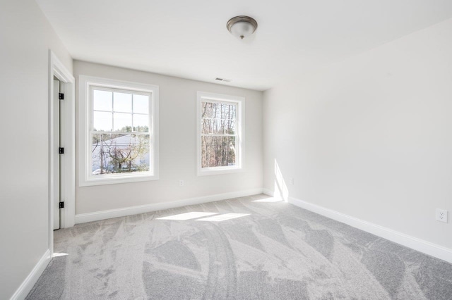 carpeted spare room featuring visible vents and baseboards