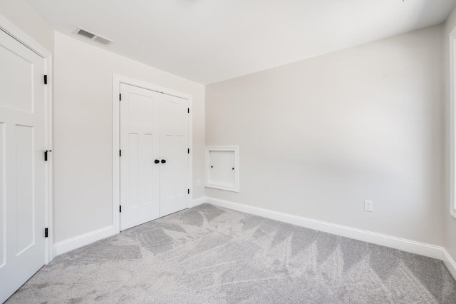 unfurnished bedroom with a closet, visible vents, baseboards, and carpet floors