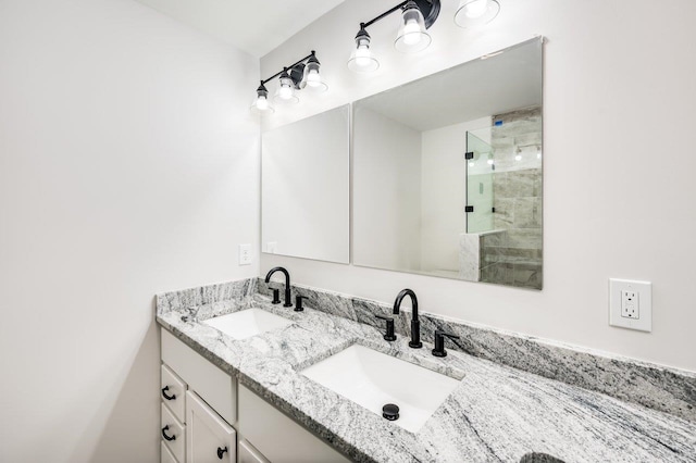 full bath with double vanity, tiled shower, and a sink