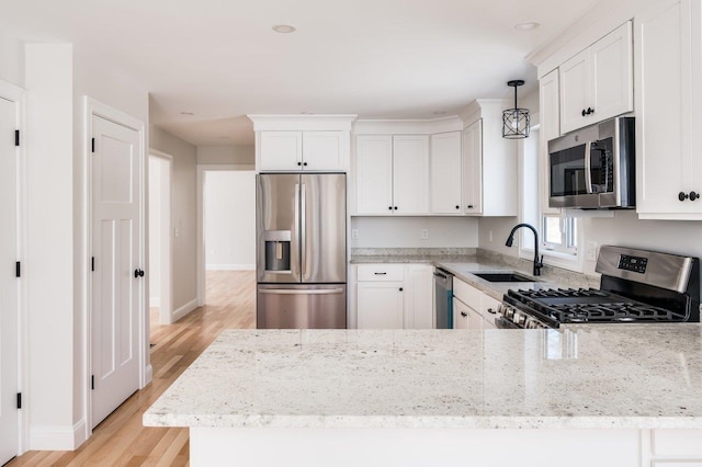 kitchen with light wood-type flooring, light stone counters, white cabinets, stainless steel appliances, and a sink