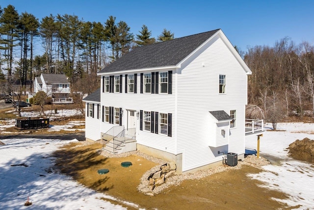 view of front facade with central AC unit and a shingled roof