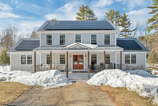 view of front facade with a standing seam roof, a porch, and french doors