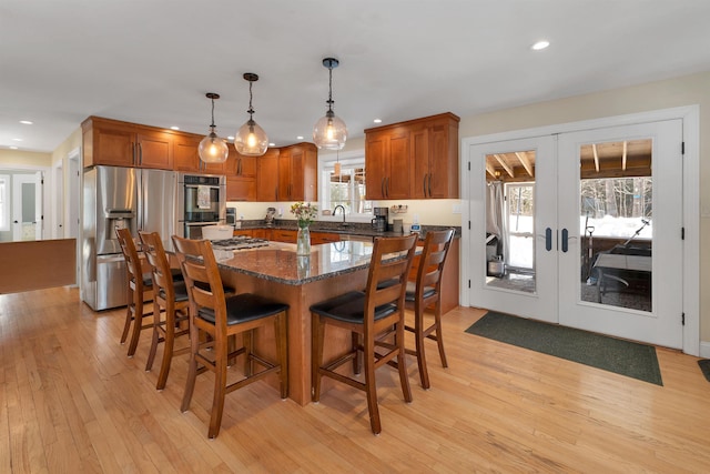 kitchen featuring brown cabinets, french doors, light wood-type flooring, and stainless steel appliances