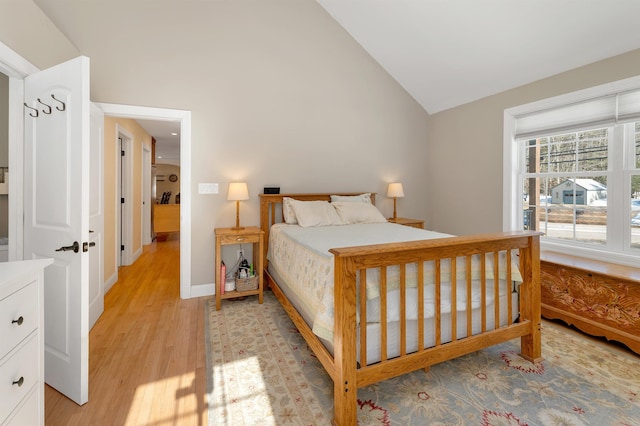 bedroom with baseboards, light wood-type flooring, and high vaulted ceiling