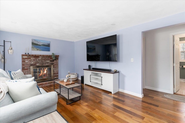 living area featuring a brick fireplace, wood finished floors, and baseboards