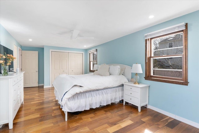 bedroom with a ceiling fan, wood finished floors, recessed lighting, a closet, and baseboards