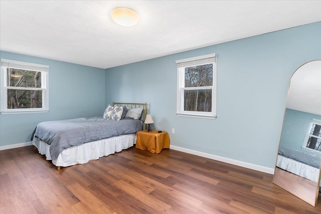 bedroom with baseboards, multiple windows, and wood finished floors