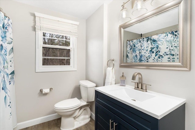 bathroom featuring baseboards, toilet, wood finished floors, and vanity