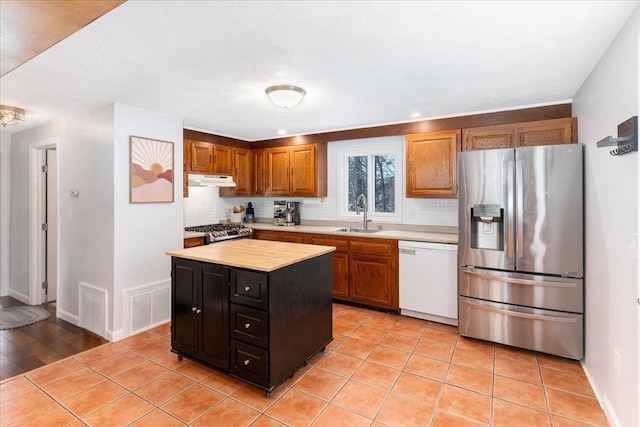 kitchen featuring tasteful backsplash, light countertops, white dishwasher, stainless steel fridge, and a sink