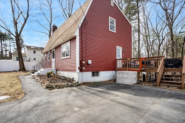 view of home's exterior featuring a wooden deck, fence, and a chimney