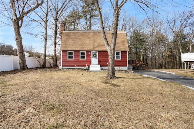 colonial inspired home with a front yard, fence, driveway, and a chimney