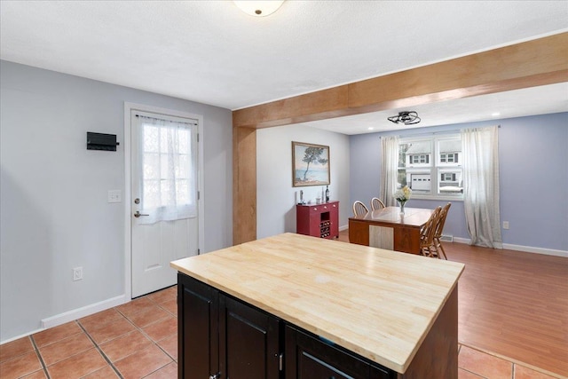 kitchen with light tile patterned floors, baseboards, butcher block countertops, and a center island