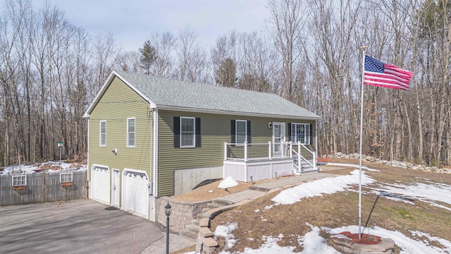 view of front of property featuring aphalt driveway, an attached garage, a forest view, and roof with shingles