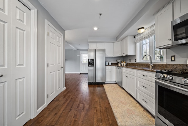 kitchen featuring a sink, dark wood-style floors, white cabinetry, stainless steel appliances, and baseboards