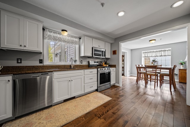 kitchen with a healthy amount of sunlight, appliances with stainless steel finishes, dark wood-type flooring, and a sink