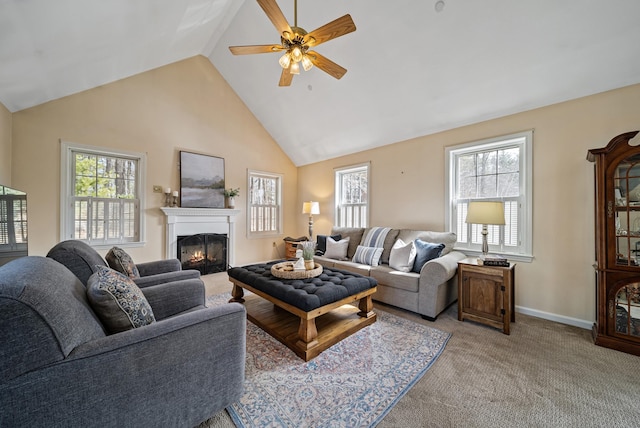 living area featuring a ceiling fan, baseboards, high vaulted ceiling, a lit fireplace, and light carpet