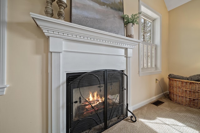 room details featuring carpet flooring, visible vents, a warm lit fireplace, and baseboards