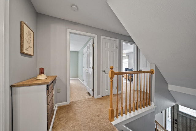 hall with baseboards, an upstairs landing, and light colored carpet