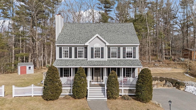 view of front facade featuring roof with shingles, a porch, and driveway