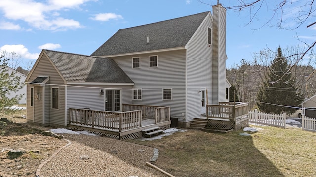 back of house featuring a shingled roof, a wooden deck, fence, and a chimney