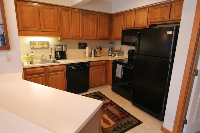 kitchen featuring a sink, black appliances, brown cabinetry, and light countertops