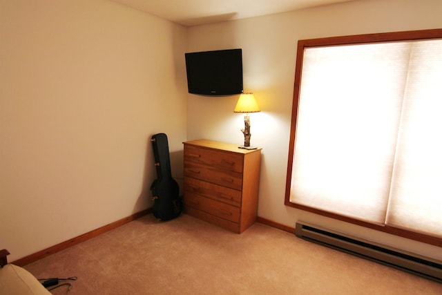 bedroom featuring light colored carpet, a baseboard heating unit, and baseboards