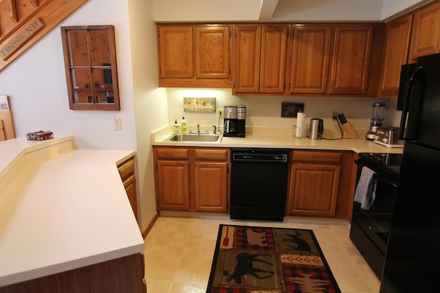 kitchen featuring brown cabinets, black appliances, a sink, a peninsula, and light countertops