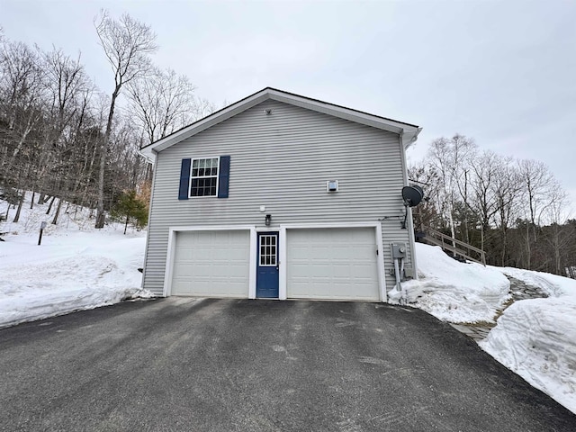 snow covered property with a garage and driveway