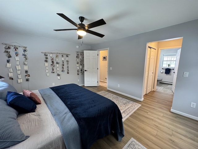 bedroom featuring ceiling fan, ensuite bathroom, baseboards, and wood finished floors