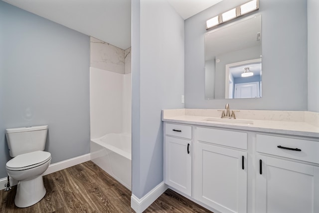 bathroom with vanity, wood finished floors, baseboards, shower / bathing tub combination, and toilet