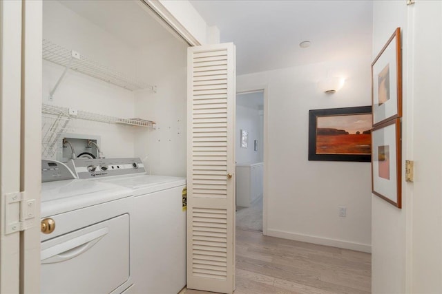 washroom featuring baseboards, light wood-style flooring, laundry area, and washing machine and clothes dryer