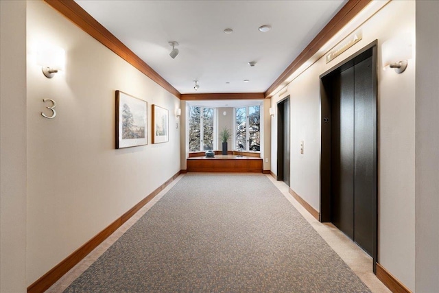 hallway with baseboards, elevator, light carpet, and ornamental molding