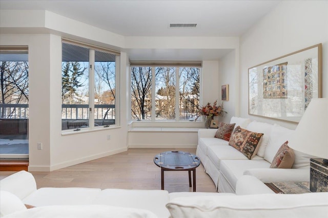 living room with visible vents, a healthy amount of sunlight, baseboards, and wood finished floors