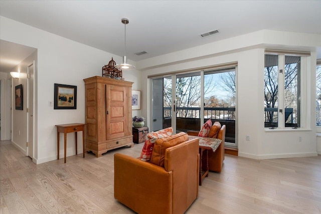 living room featuring visible vents, light wood-style flooring, and baseboards