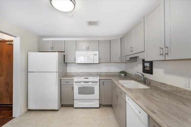 kitchen featuring white appliances, gray cabinets, and a sink