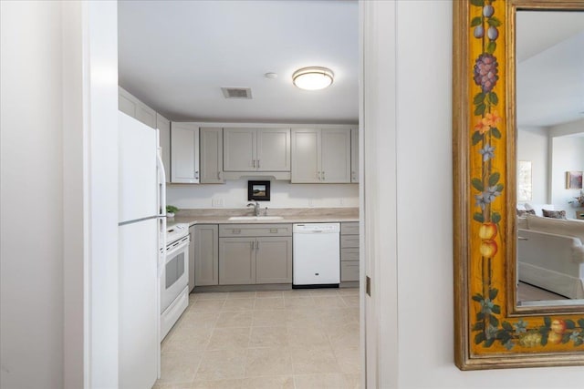 kitchen with white appliances, visible vents, gray cabinets, a sink, and light countertops