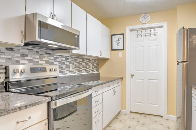 kitchen with backsplash, light floors, appliances with stainless steel finishes, white cabinets, and a textured ceiling